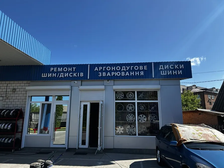Окреме крило магазину Шина Сервіс з дисками у вітрині та шинами біля входу